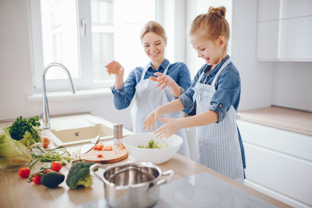 goede voornemens, koken meisje, samen koken, mooie-moeder-in-een-blauw-shirt-en-schort-bereidt-thuis-een-verse-groente-salade_1157-13945