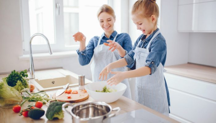 goede voornemens, koken meisje, samen koken, mooie-moeder-in-een-blauw-shirt-en-schort-bereidt-thuis-een-verse-groente-salade_1157-13945